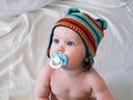 Baby boy in bright hat with pacifier