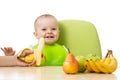 Baby having a table full of healthy food. Cheerful toddler with fruits apples, bananas, pear. Isolated on white Royalty Free Stock Photo