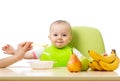 Baby having a table full of healthy food. Cheerful toddler with fruits apples, bananas, pear. Isolated on white Royalty Free Stock Photo