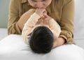 Mother holding head of her newborn baby on one hand and kissing baby hand. Loving mum hand holding sleeping infant child on bed Royalty Free Stock Photo