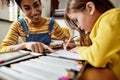 Baby helper. Close up of caucasian little girl spending time with her african american nanny. Kid is writing, learning Royalty Free Stock Photo