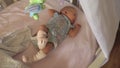 Baby with hiccup lying in crib with toy mobile