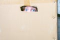 The baby hid in a cardboard box and is afraid. A child with wide open eyes sits in a mail box. The frightened blue eyes of a Royalty Free Stock Photo