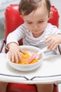 Baby, high chair and eating food in bowl for meal, nutrition or healthy porridge at home. Young, cute and adorable Royalty Free Stock Photo