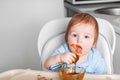 Baby in highchair covered in fruit, vegetable puree close-up. Complementary feeding tredhead oddler concept