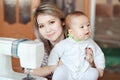 Baby with his mother, home, natural light, curiously looking directly into camera. Near the sewing machine. Child care Royalty Free Stock Photo