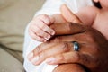 Baby holding father`s hand. Multiracial diverse family. Royalty Free Stock Photo