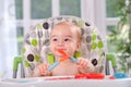 Baby holding itself with a spoon and fork