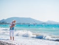 Baby hugging mother standing at sea shore