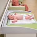 The baby infant boy lies in a diaper on the changing table in the clinic. Happy child changing clothes on nappy before appointment Royalty Free Stock Photo