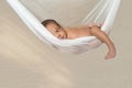 Baby infant three weeks old boy relaxing on a clear white see-through hammock hanging smiling peeping looking at the camera making