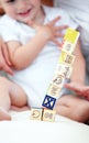 Baby, kid and playing with blocks for learning, smile and happy in home nursery on bed. Toddler, wood and child with Royalty Free Stock Photo