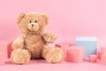 Baby kid toys background. Blue empty rectangle podium platform stand, teddy bear and pink wooden toy blocks on pastel Royalty Free Stock Photo
