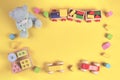 Baby kids educational toys background. Teddy bear, wooden train, car, colorful wood toys and bricks on pastel yellow Royalty Free Stock Photo