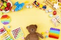 Baby kids toy frame with teddy bear, wooden and musical toys, abacus, plane, pop it fidget toys on yellow background Royalty Free Stock Photo