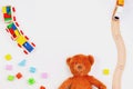 Baby kids toys background. Teddy bear, wooden train, colorful bricks on white table