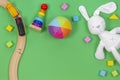 Baby kids toys background with toys train, colorful wooden blocks and soft plush toys on light green background.