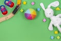 Baby kids toys background with toys train, colorful wooden blocks and soft plush toys on light green background.