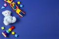 Baby kids toys background. Wooden train, blue teddy bear, stacking pyramid tower and colorful blocks on navy blue Royalty Free Stock Photo