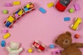 Baby kids toys frame with teddy bear, toy car, wooden train, colorful bricks on pink background. Top view Royalty Free Stock Photo