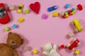 Baby kids toys frame with teddy bear, wooden toy car, colorful bricks on pink background. Top view Royalty Free Stock Photo