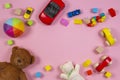 Baby kids toys frame with teddy bear, wooden toy car, colorful bricks on pink background. Top view Royalty Free Stock Photo