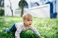 Baby is kneeling on the lawn among white daisies