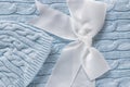 Baby knitted hat on a soft gray blue blanket. Cute gift for newborn baby with decorative white bow