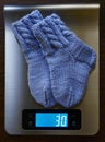 Baby knitted woolen socks on the scales