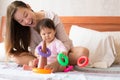 Baby learning coordination skills while laying, and a happy proud mother watching her child with glee