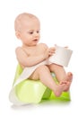 Baby learning how to use chamber pot. sitting on the potty with toilet paper rolls on white background