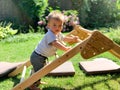 Baby learning to stand and climb on a wooden triangle
