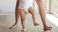 Baby, learning and walking with a child taking its first steps with his mother to learn to walk at home. Feet, legs and