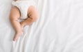 Baby legs and bottom in diaper on bed Royalty Free Stock Photo