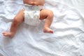 Baby legs and bottom in diaper on white bed background, top view, copy space Royalty Free Stock Photo