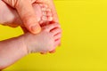 Baby legs on a yellow background, the mother holds the small legs of a newborn baby in her hand Royalty Free Stock Photo