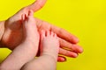 Baby legs on a yellow background, the mother holds the small legs of a newborn baby in her hand Royalty Free Stock Photo