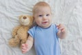 The baby lies on the floor with a teddy bear. A child waving his Royalty Free Stock Photo