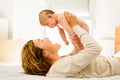 Baby lifted in arms by his mother lying on the bed while playing newly awakened happy