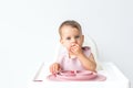 baby little sits in a high chair and eats complementary foods. , close-up portrait looks at the camera. baby food concept