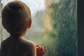 Baby is looking to rain through the window standing with back Royalty Free Stock Photo