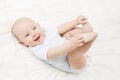 Baby Lying on Back, Happy Smiling Kid Holding Legs in Hands Royalty Free Stock Photo