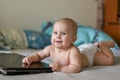 The baby is lying in a bed with blue bedclothes. There is a notebook in front of a girl