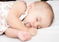 Baby lying on a bed while sleeping in a bright room Royalty Free Stock Photo