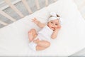 The baby is lying in the crib in the children`s room on a white bed and sucking his finger Royalty Free Stock Photo