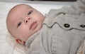 Baby lying with a grey sweater looks carefully Royalty Free Stock Photo