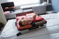Baby lying in an open suitcase containing clothes