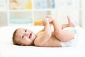 Baby lying on white bed and holding legs Royalty Free Stock Photo