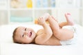 Baby lying on white bed and holding legs Royalty Free Stock Photo