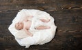 Baby lying on white blanket designed as cloud or nest.